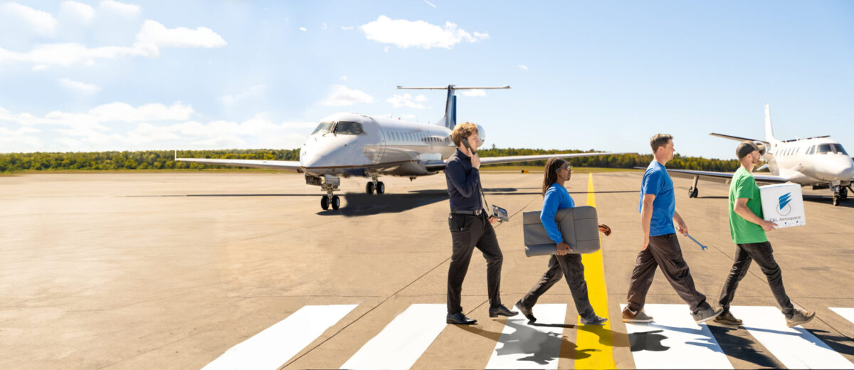 A photo of four C&L employees carrying their respective tools walking across a runway in a fashion similar to the cover of The Beatles' "Abbey Road"