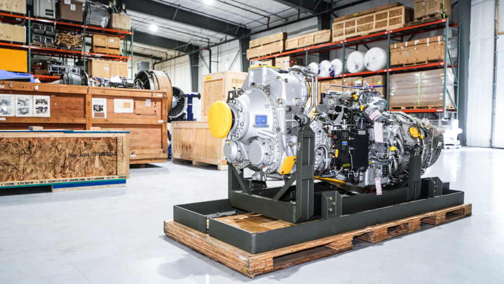 A large airplane engine standing on a wooden pallet in a warehouse