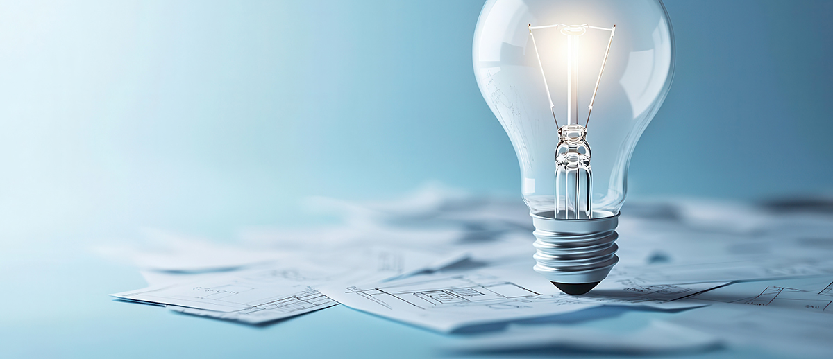 A graphic of a lightbulb sitting on scattered layout plans on a blue background