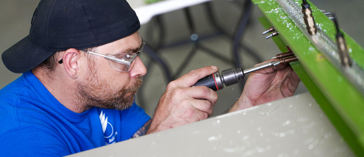 A photo of a mechanic taking a screwdriver to an airplane beam